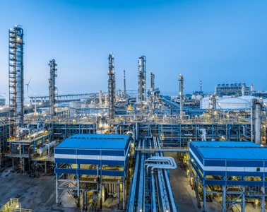 Instalaci&oacute;n de procesamiento de petr&oacute;leo y gas con torres de refiner&iacute;a y tuber&iacute;as bajo un cielo azul
