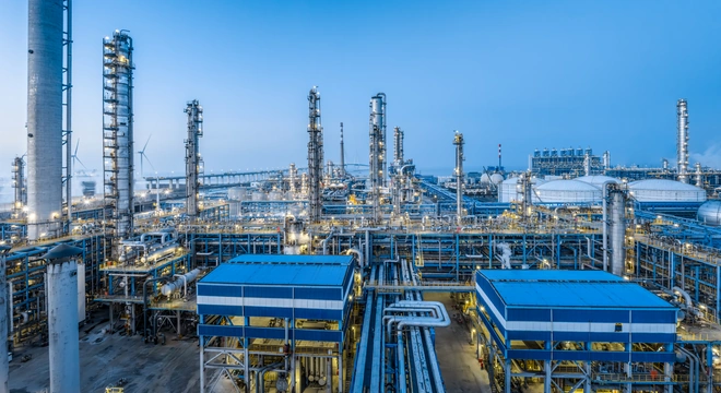 Instalaci&oacute;n de procesamiento de petr&oacute;leo y gas con torres de refiner&iacute;a y tuber&iacute;as bajo un cielo azul